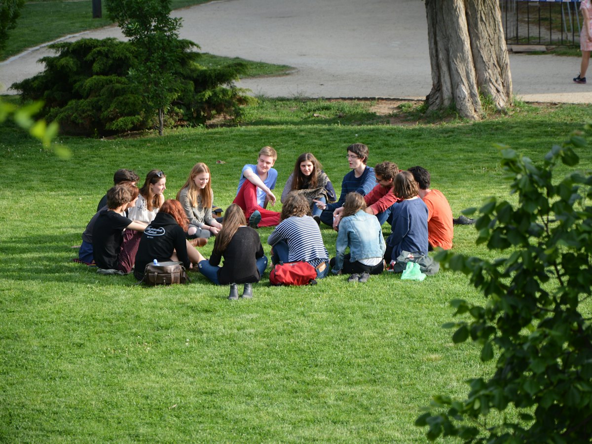 A group sitting in a circle on the grass, talking.