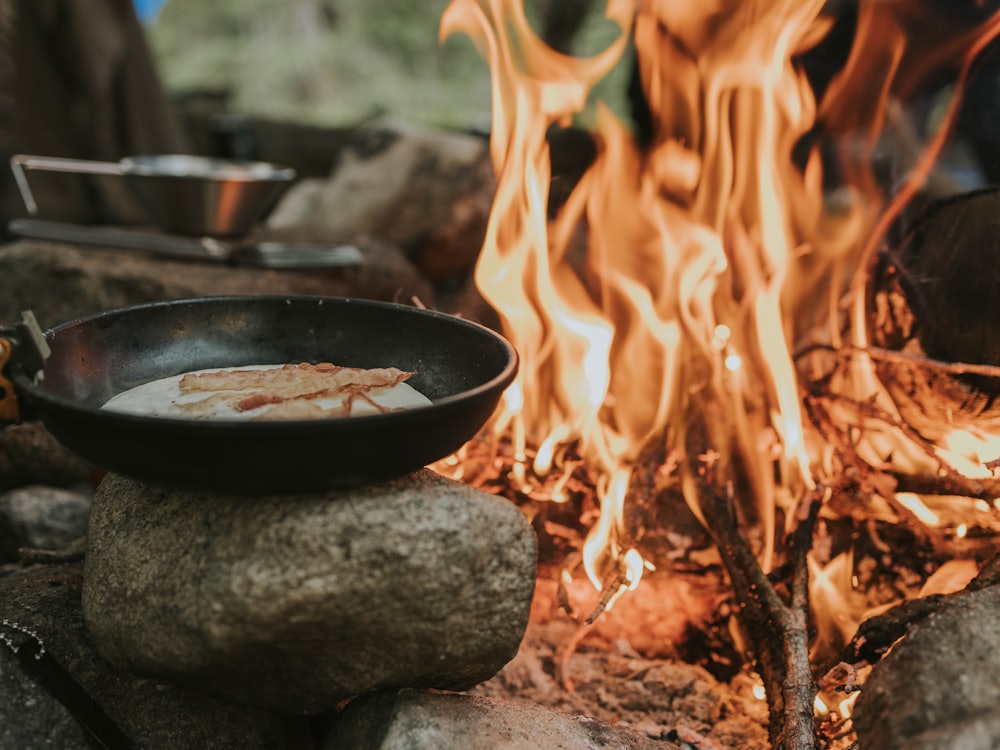 A cast iron pan over a bed of glowing coals at dusk.
