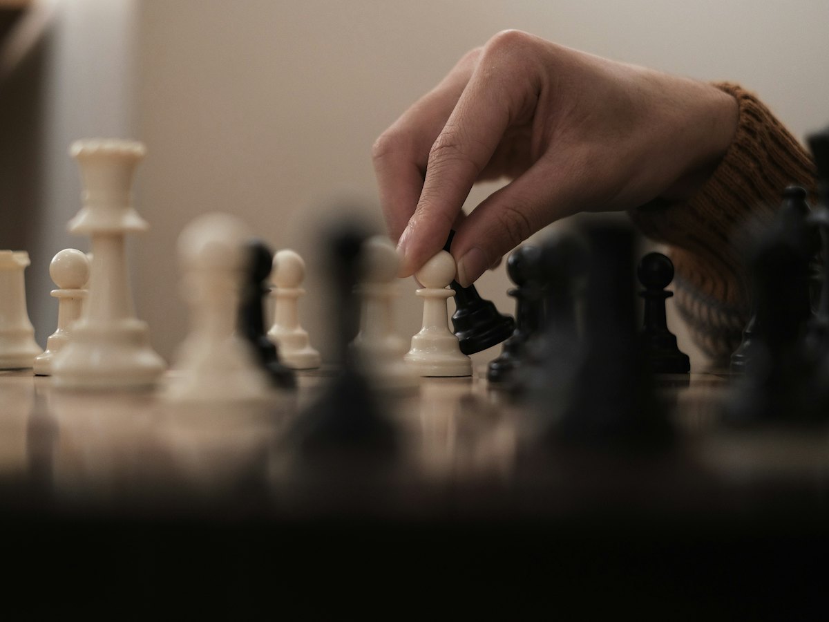 A hand moving a chess piece mid-game.
