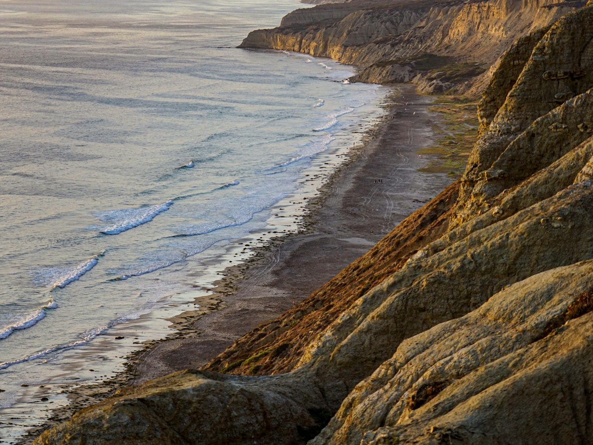 Sandstone bluffs above a long beach and the surf.