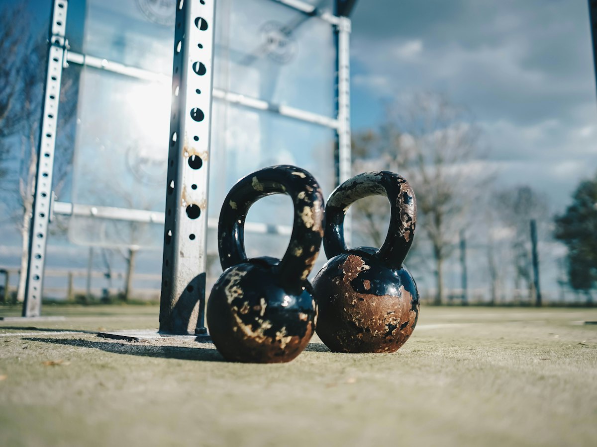 Two kettlebells on the ground at an outdoor training spot.