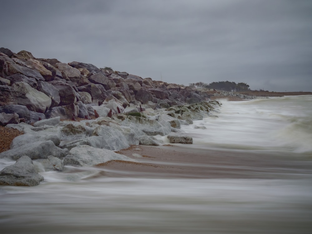 Waves breaking against a low coastal seawall below a bluff.