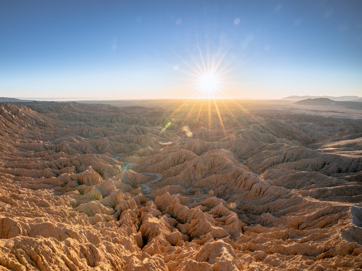 The sun rising over the eroded badlands of the desert.