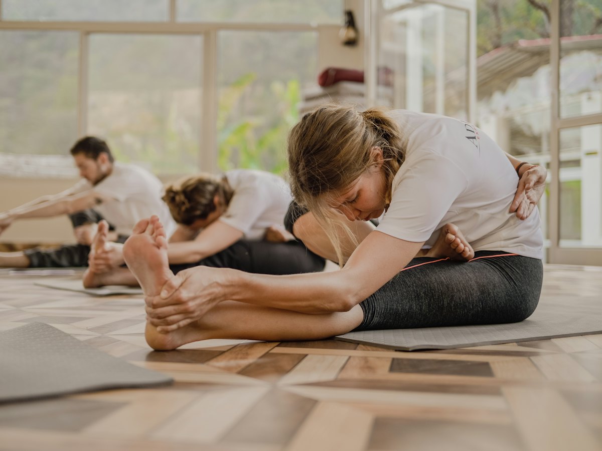 A group stretching on mats in a light-filled room.