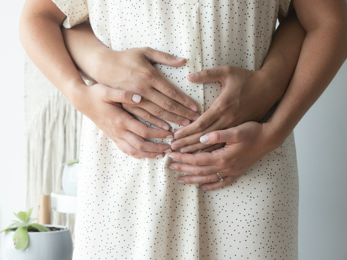 A partner's hands resting on a pregnant belly.