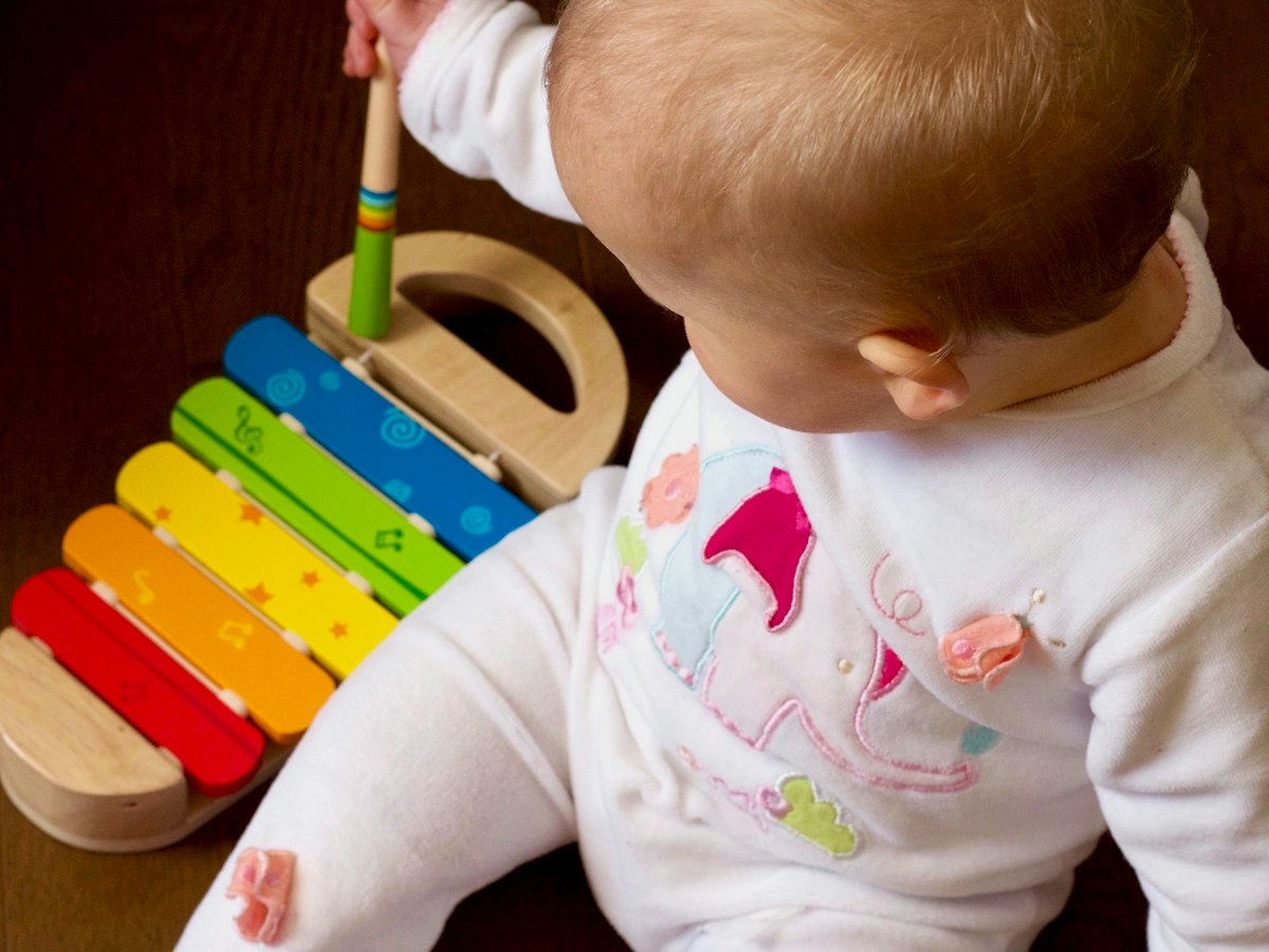 A baby playing a wooden xylophone.