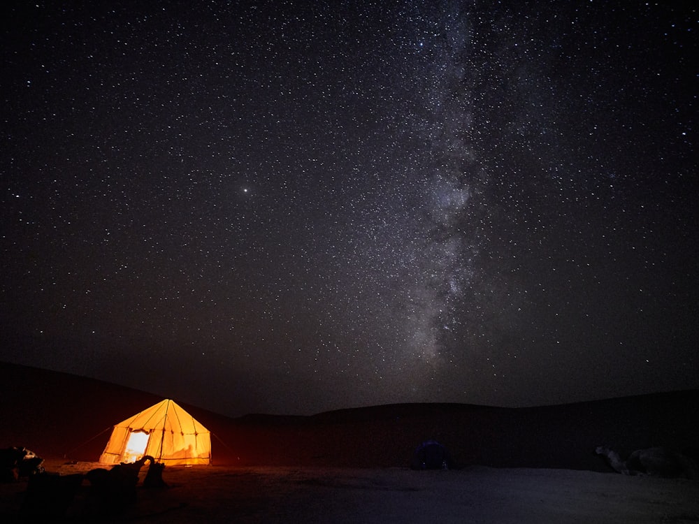 A telescope silhouetted against the Milky Way over desert scrub.