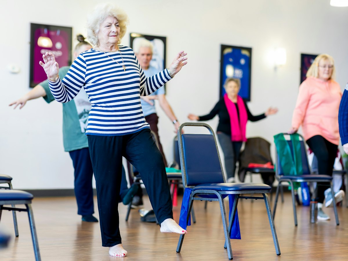 Older adults doing a seated and standing movement class.