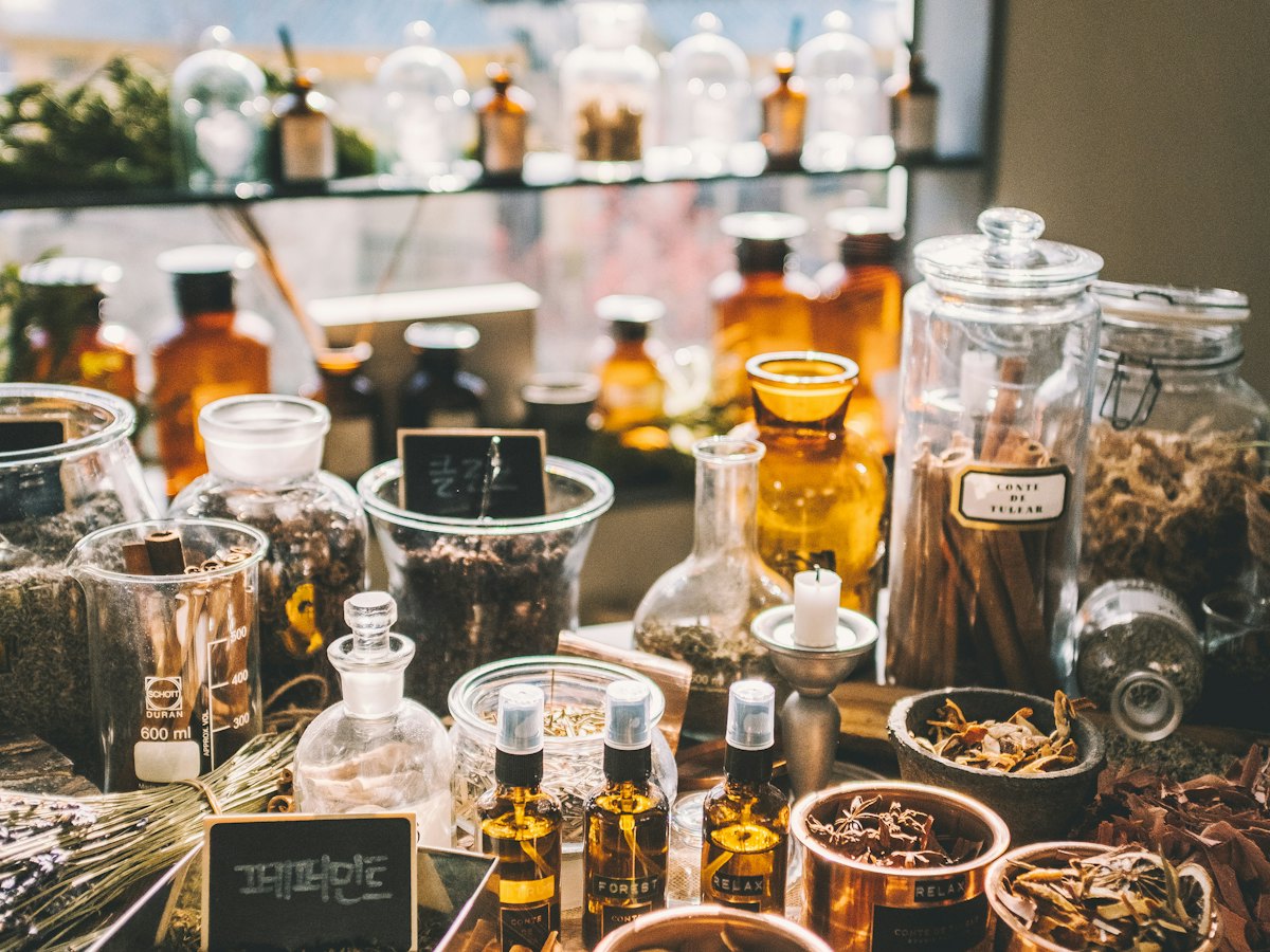 Jars of dried herbs and tinctures on an apothecary table.