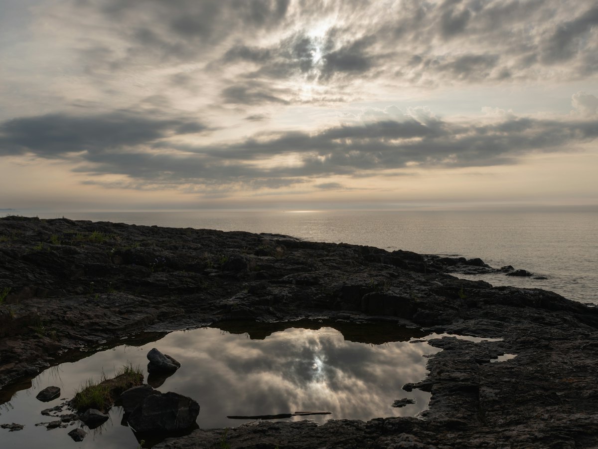 A tide pool on dark rocks at dusk.