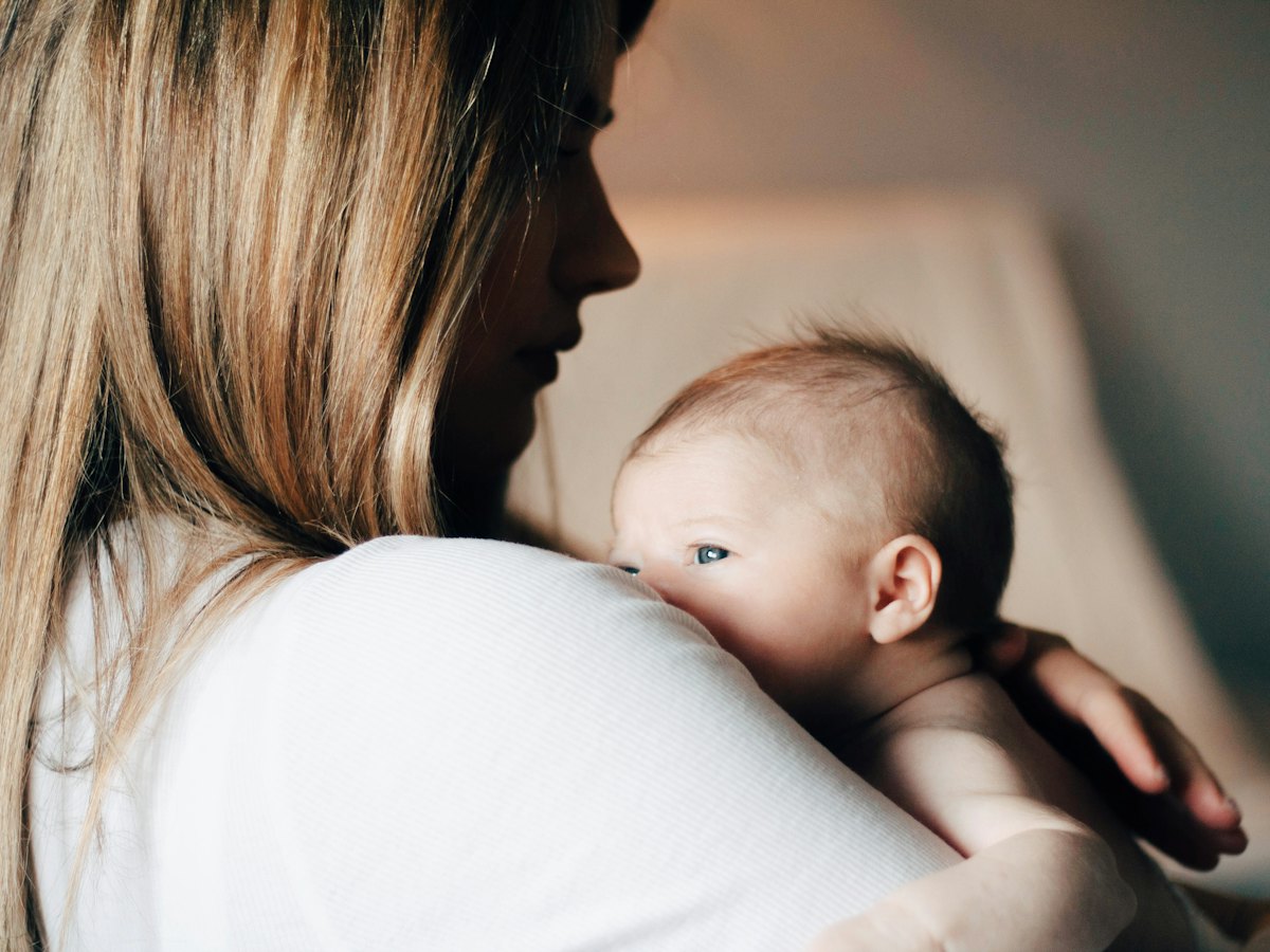 A mother holding her baby against her shoulder.