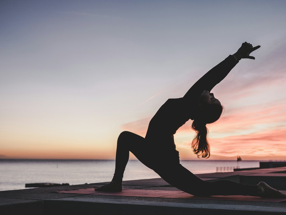 A yoga pose in silhouette against the sunrise.