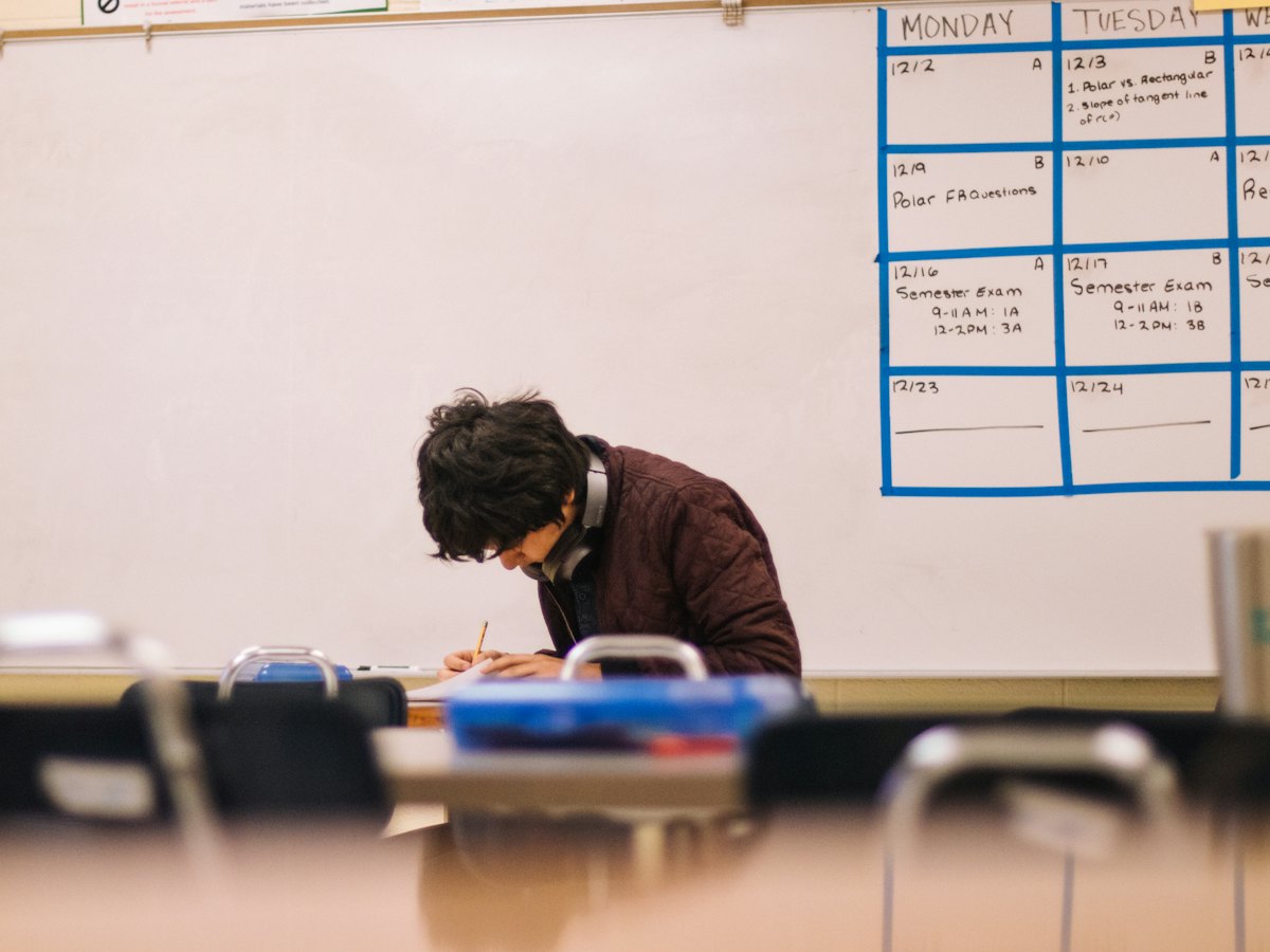 A student working alone at a desk in a classroom.
