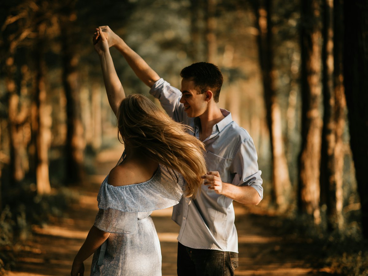 A couple dancing among the trees at golden hour.