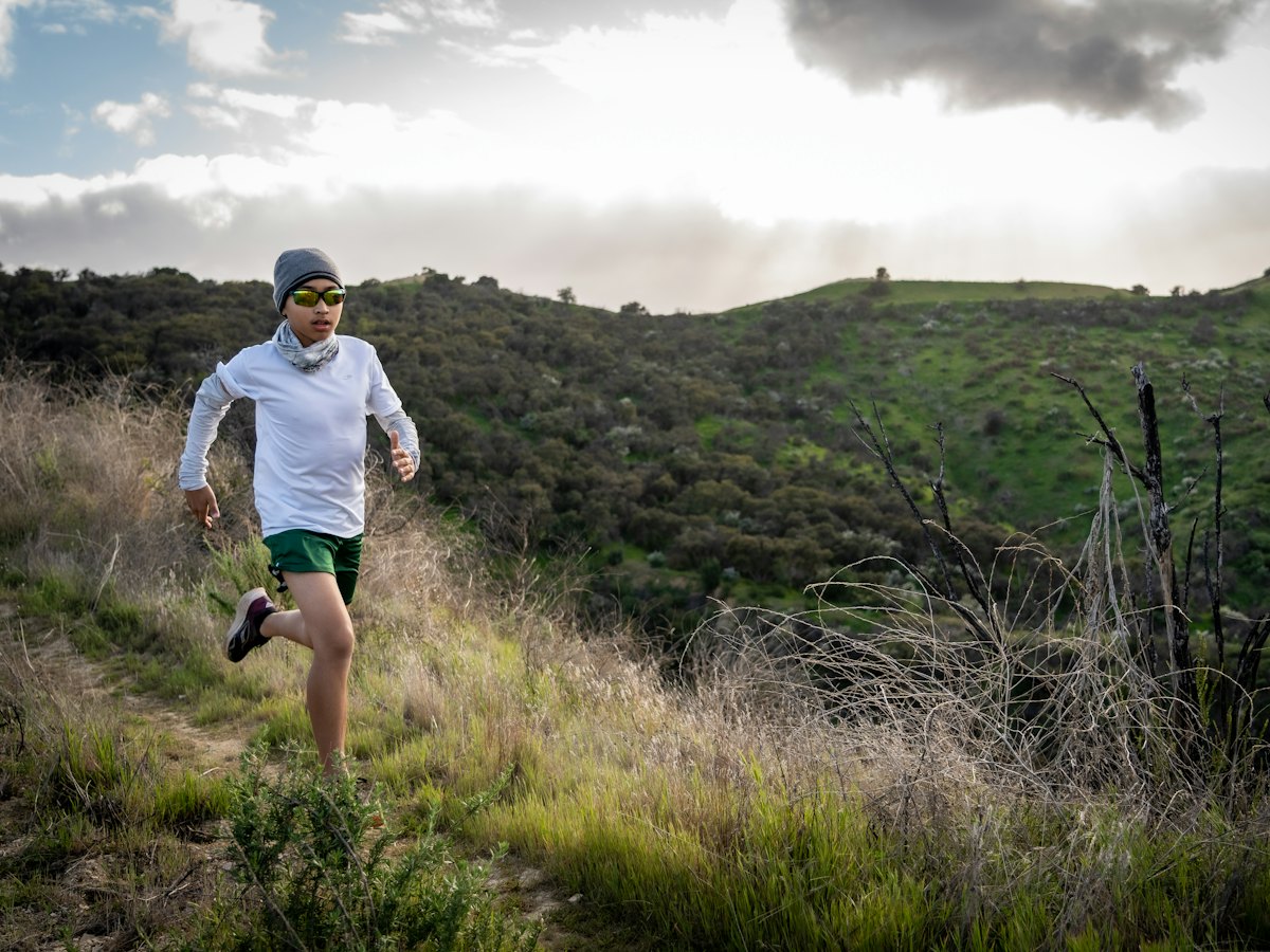 A runner on a hillside trail through scrub.