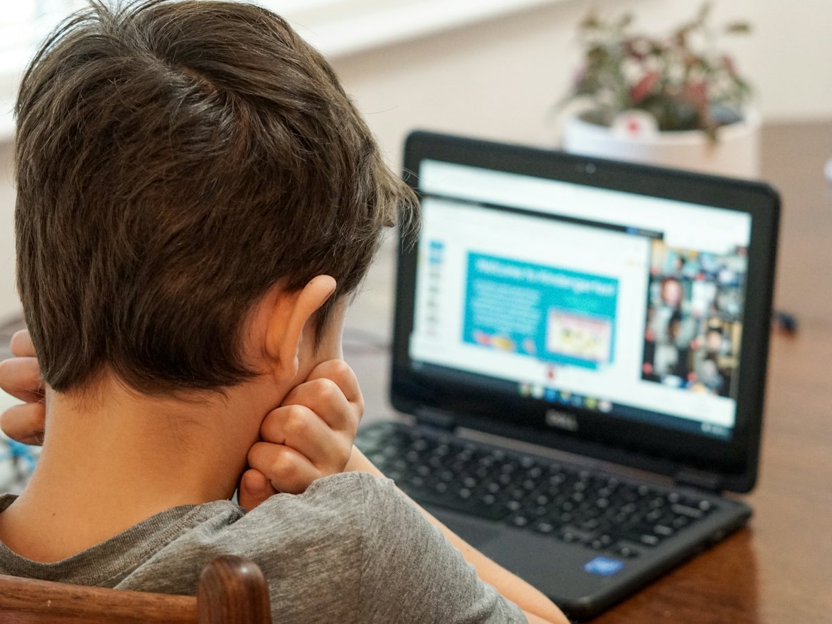 A boy working on a laptop at a table.