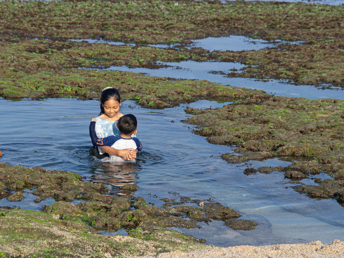 Two children wading in a tide pool.